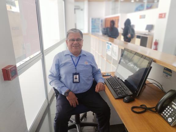 Recepcionista de la Biblioteca UCN sentado en su lugar de trabajo junto a un computador y teléfono,